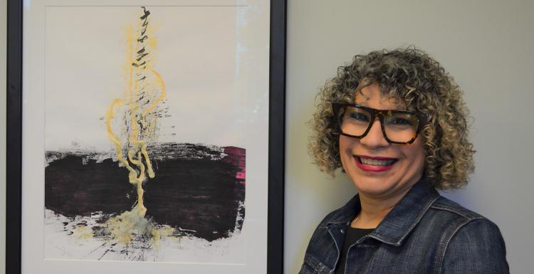 Dr. 阿尔玛·霍夫曼, 平面设计助理教授, 与她的画作“Micah 4”合影，这幅画被《十大彩票网投平台》评为2021年100件最佳艺术品之一. 